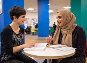 Two students in a seating area with brightly painted columns